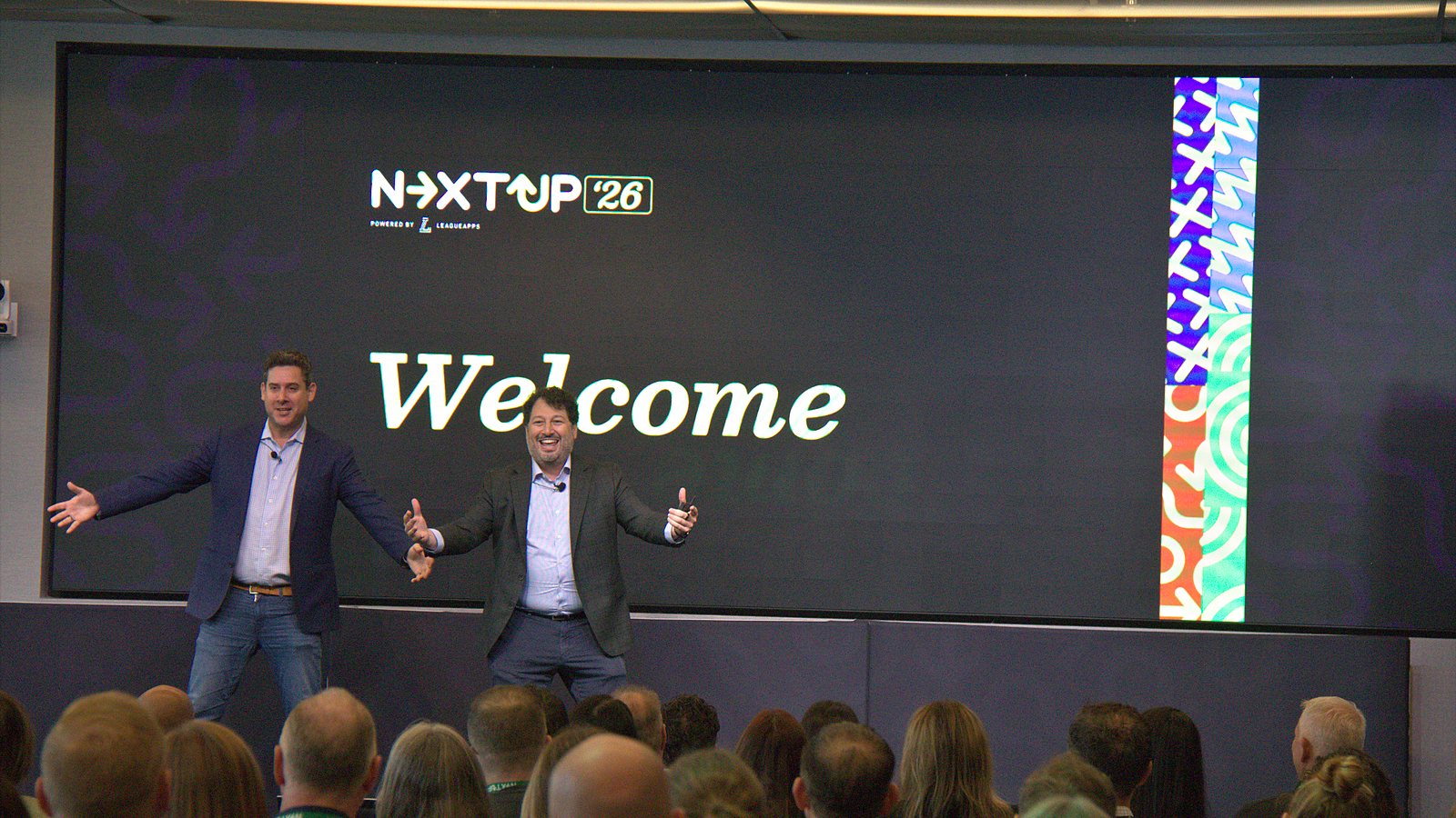 Brian Litvack and Jeremy Goldberg on stage under a Welcome slide at NextUp '26
